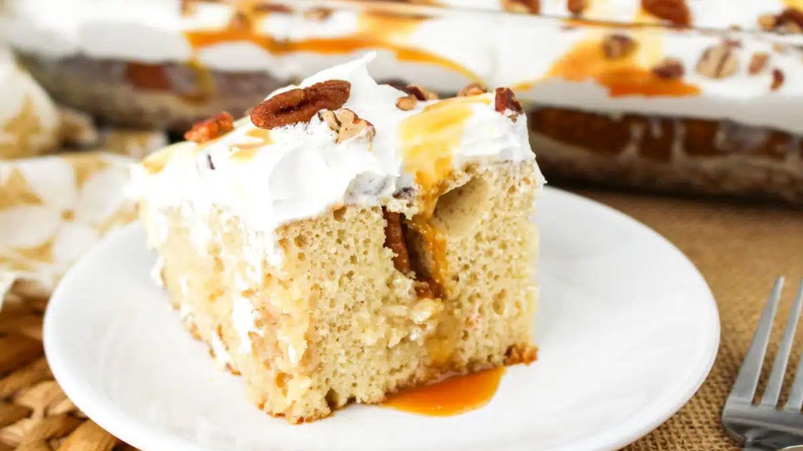 A slice of pecan poke cake on a plate.