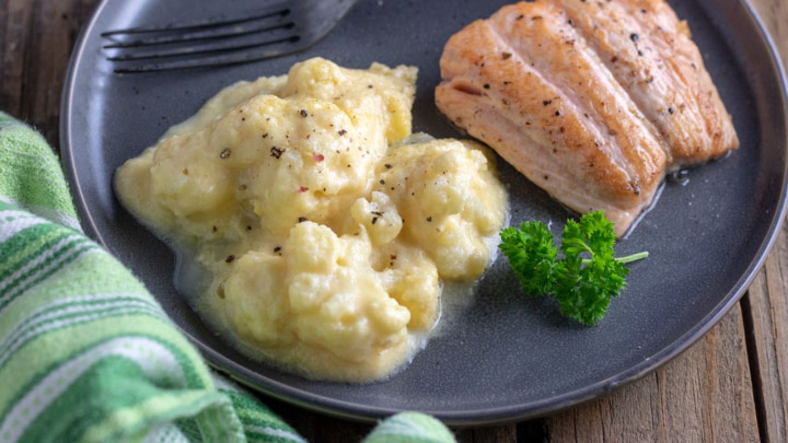 Cauliflower au gratin on gray plate with salmon filet.