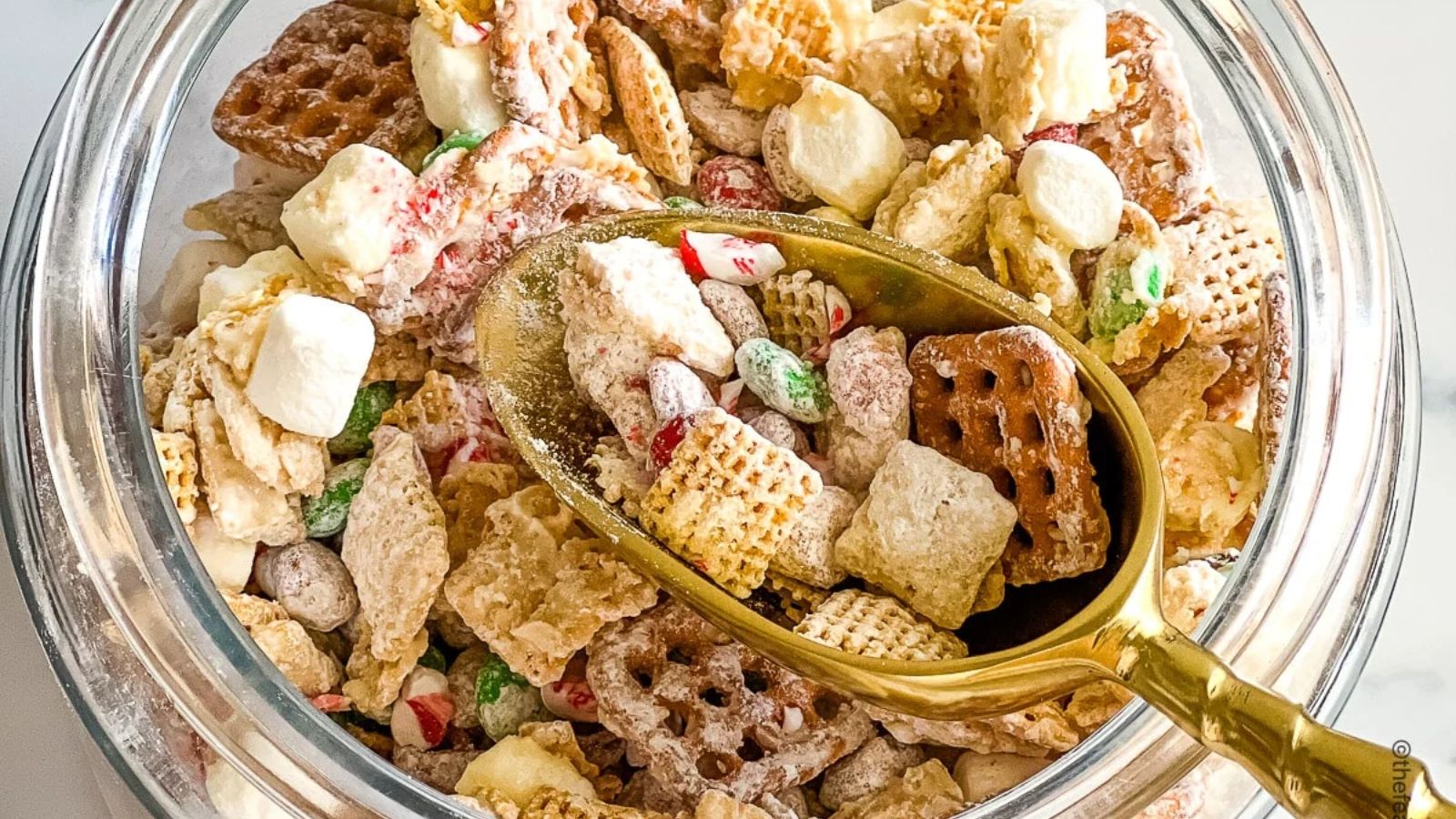 Christmas chex mix in a glass jar.