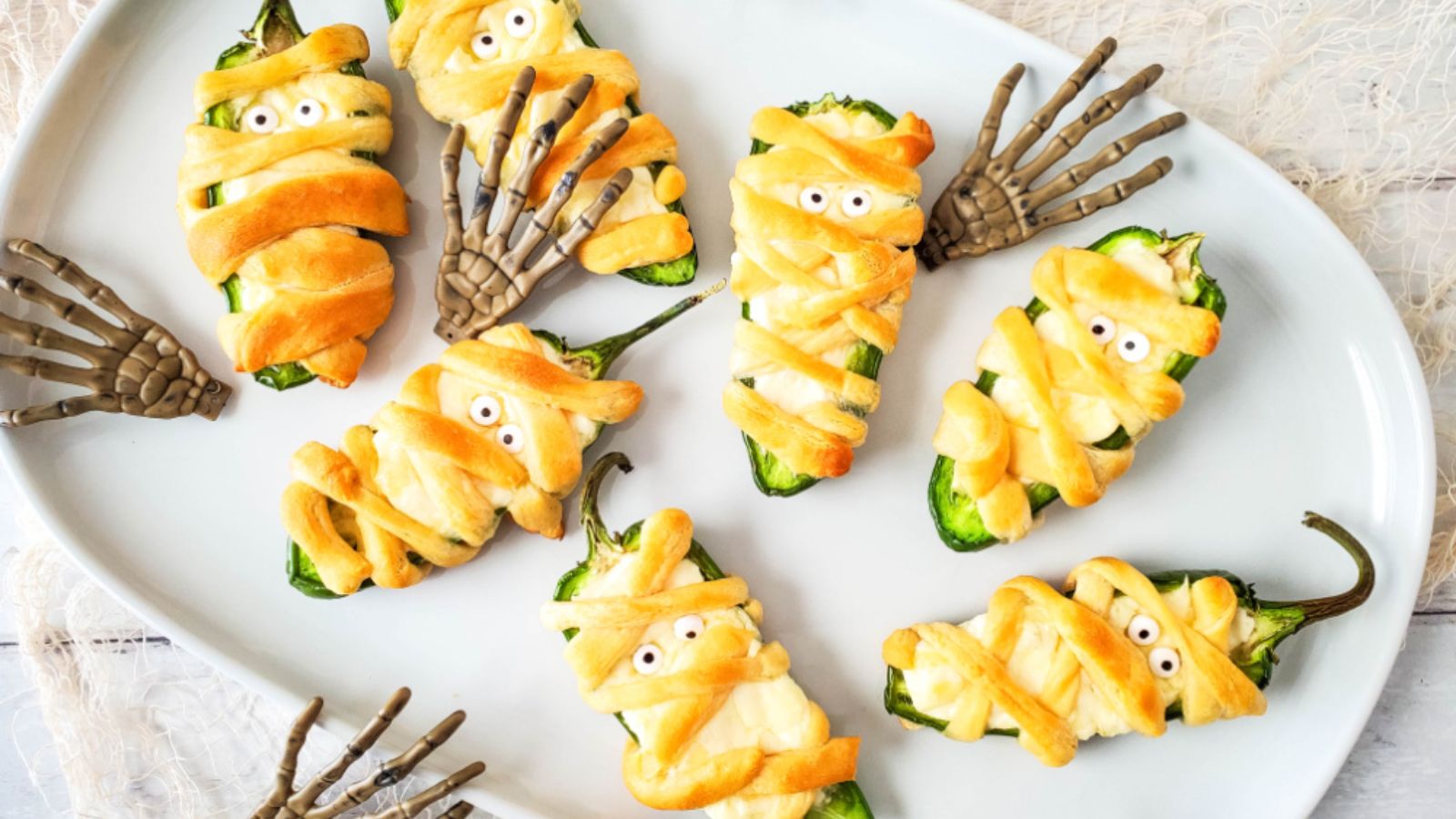 Jalapeno popper mummies on a plate.