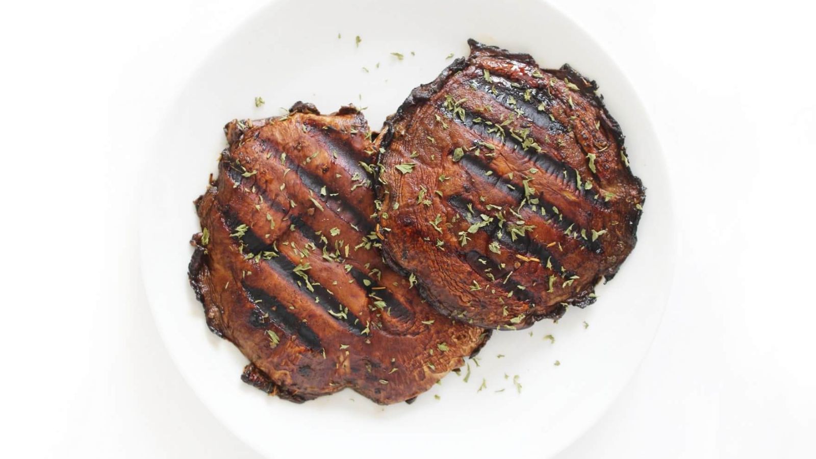 Two grilled mushroom steaks on a plate.