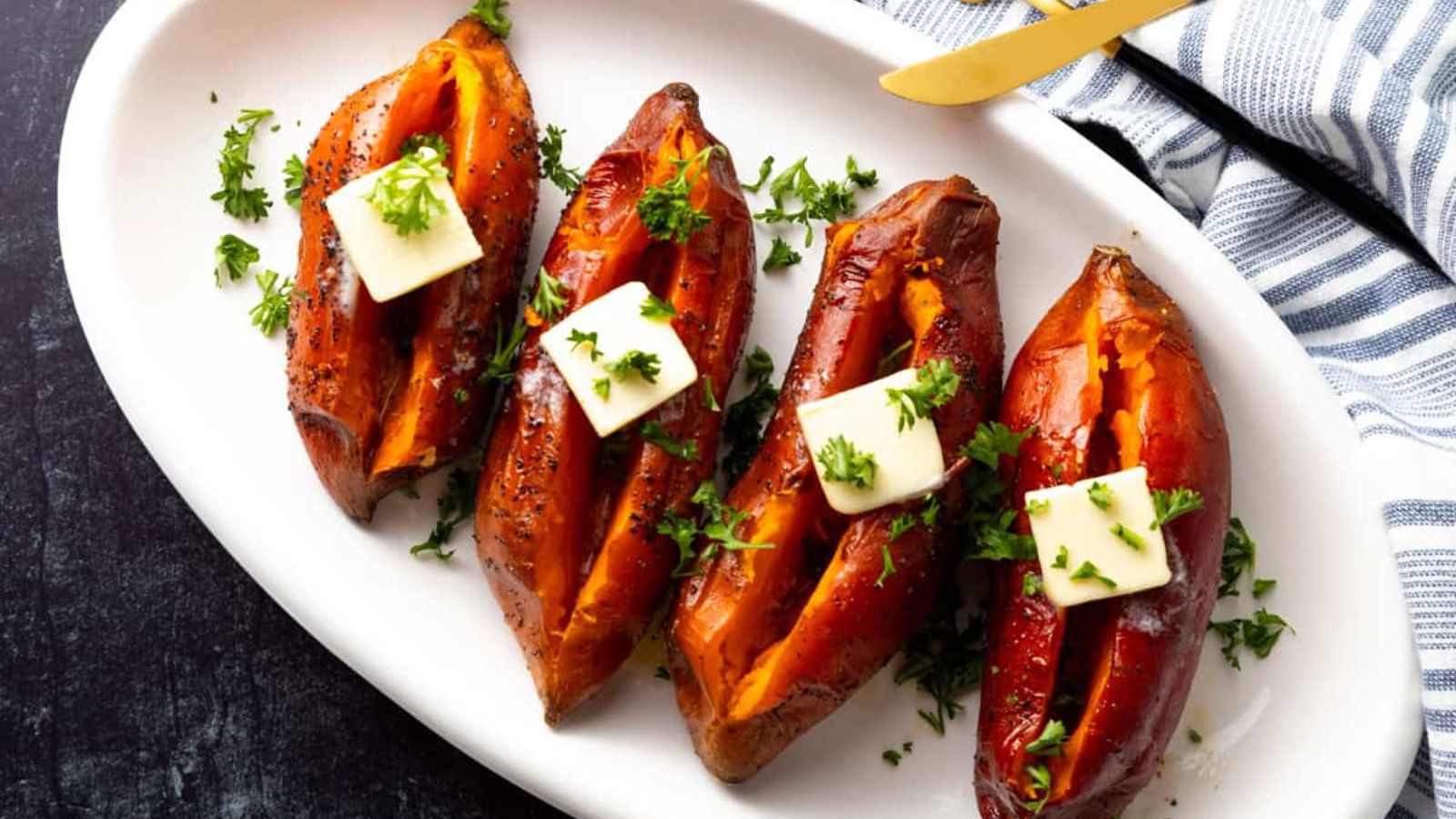 Four grilled sweet potatoes on a plate.