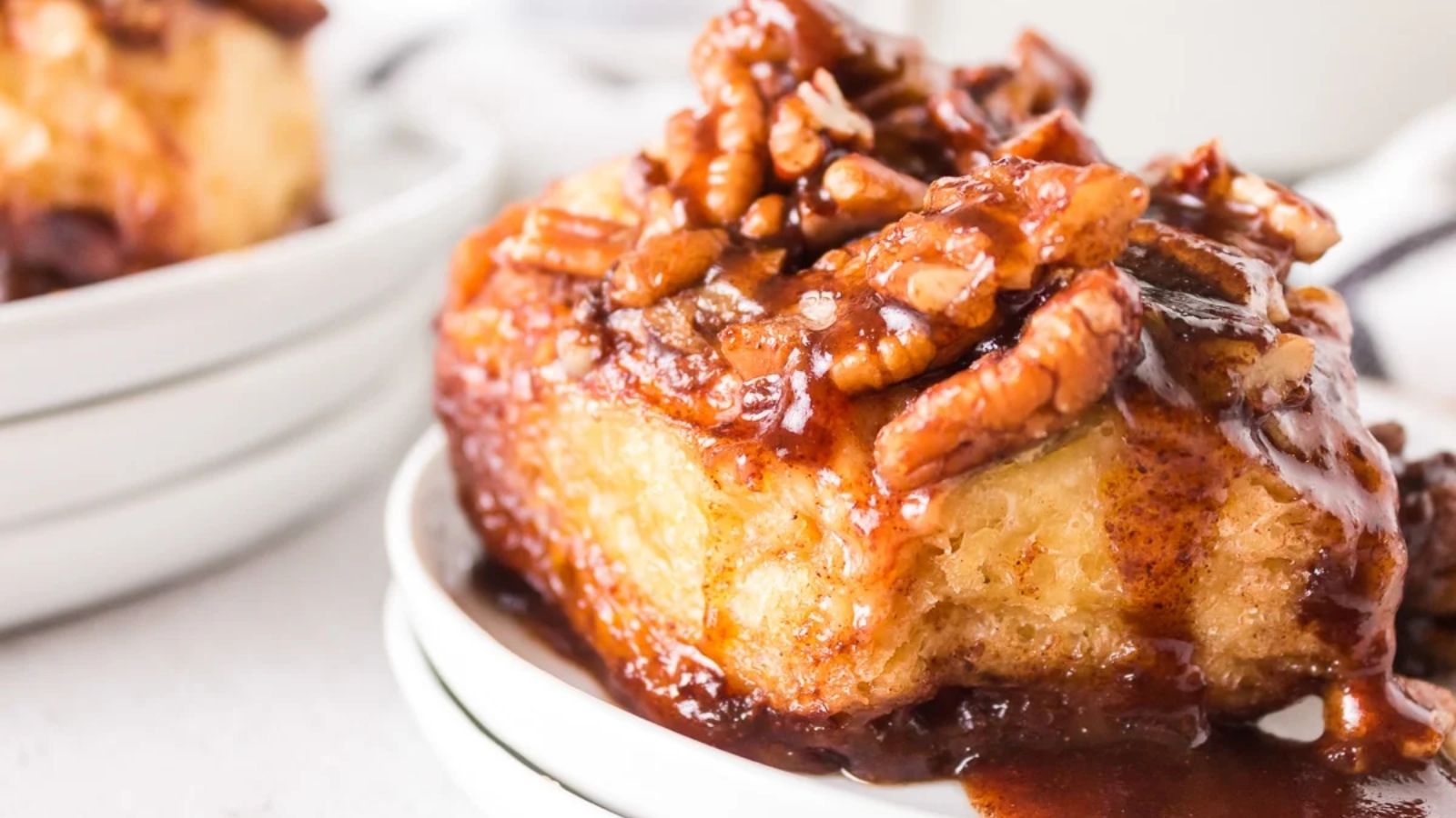 Sticky bun on a plate with sauce.