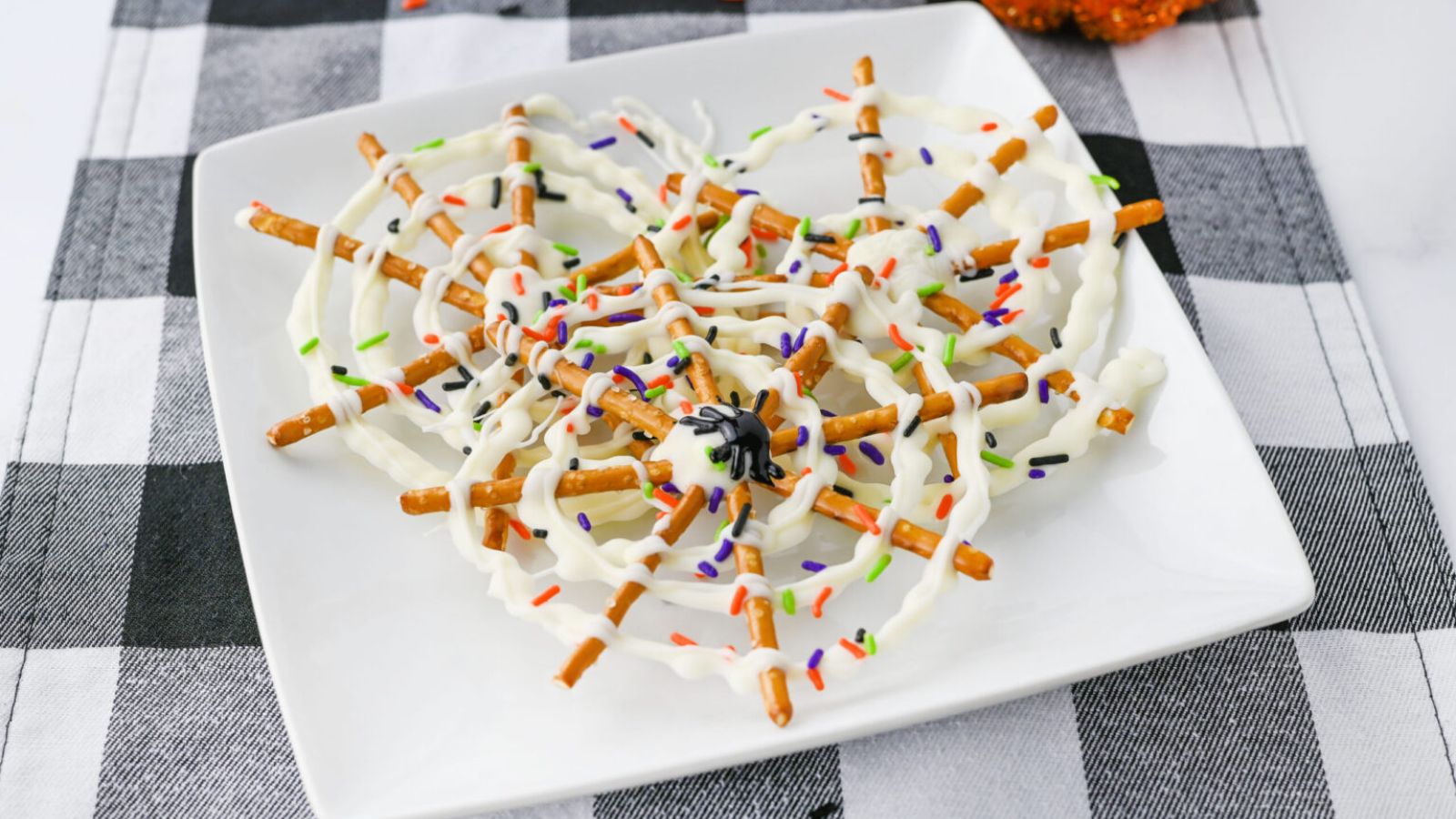 Spider web chocolate pretzels on a plate.