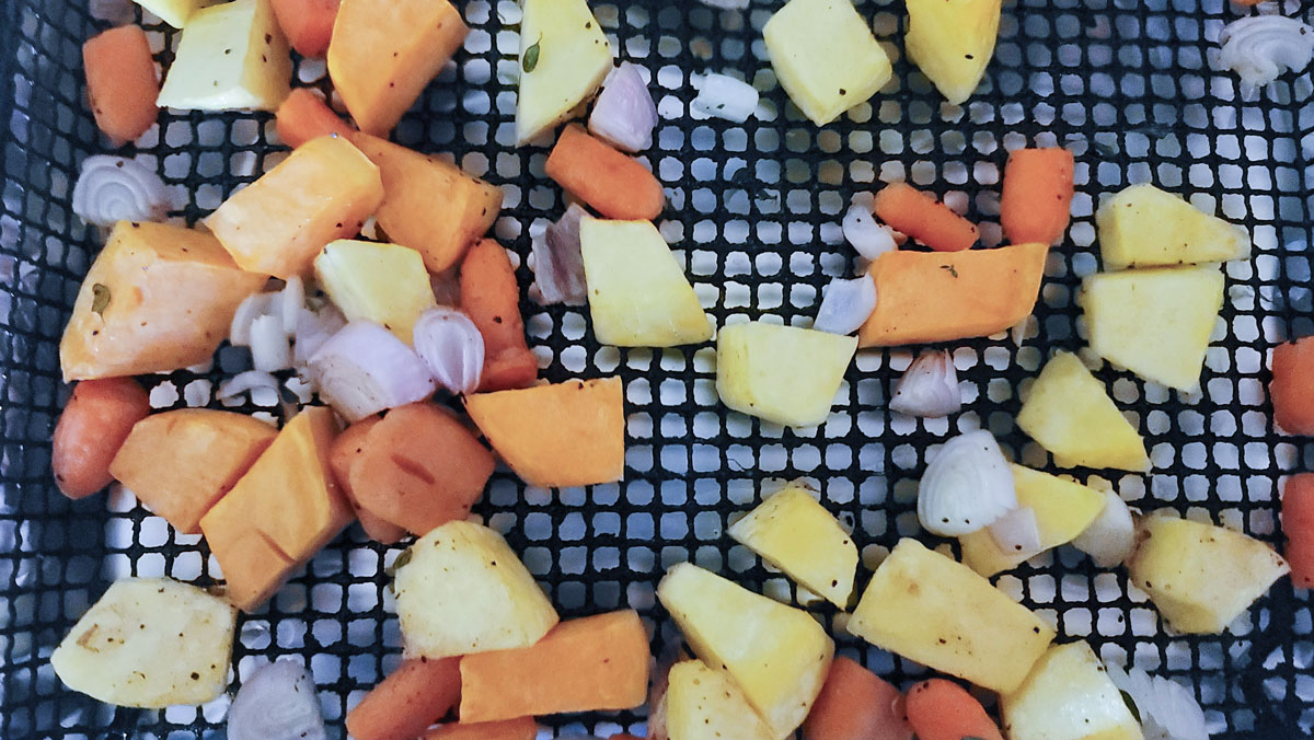 Semi roasted vegetables on the air fryer basket.