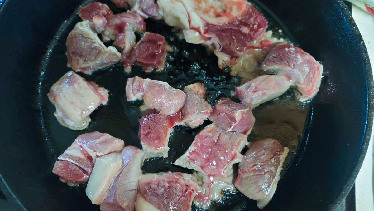 Stew meat browning in a cast iron skillet.