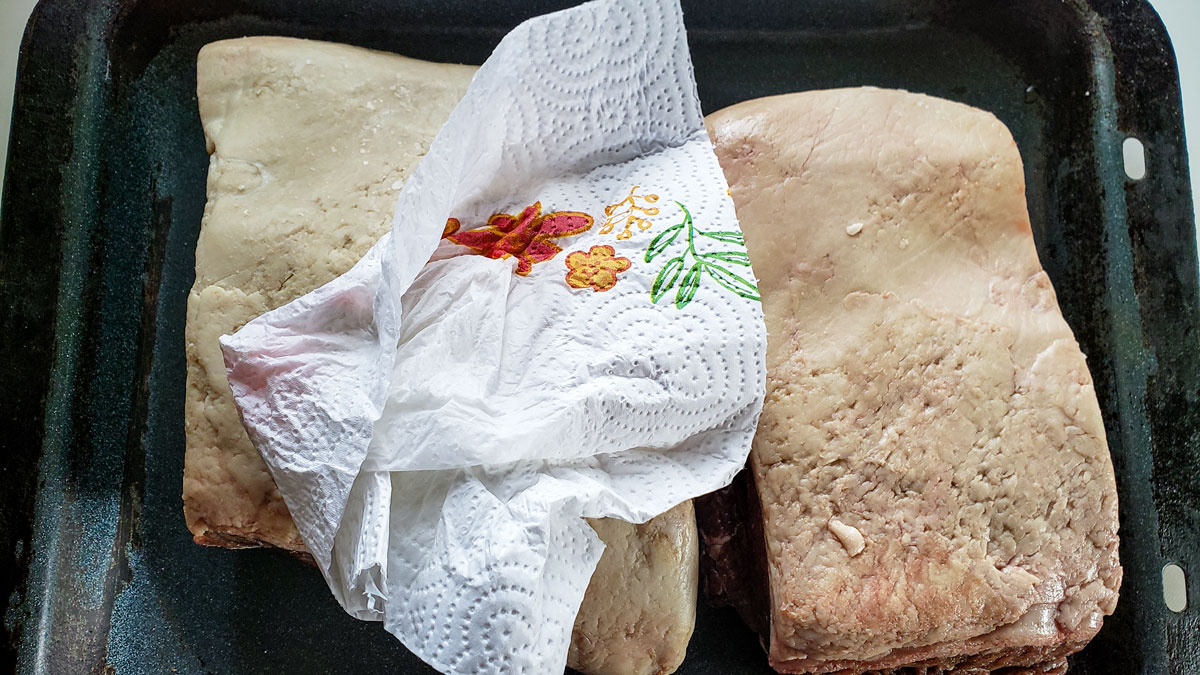 Drying off the meat with paper towel.