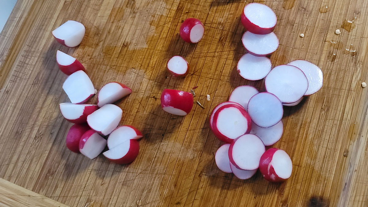 Radishes sliced on a cutting board.