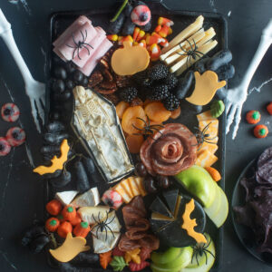 Spooky Halloween charcuterie board with a brie casket and skeleton.
