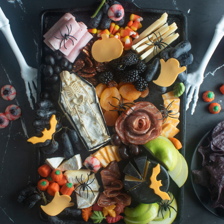 Spooky Halloween charcuterie board with a brie casket and skeleton.