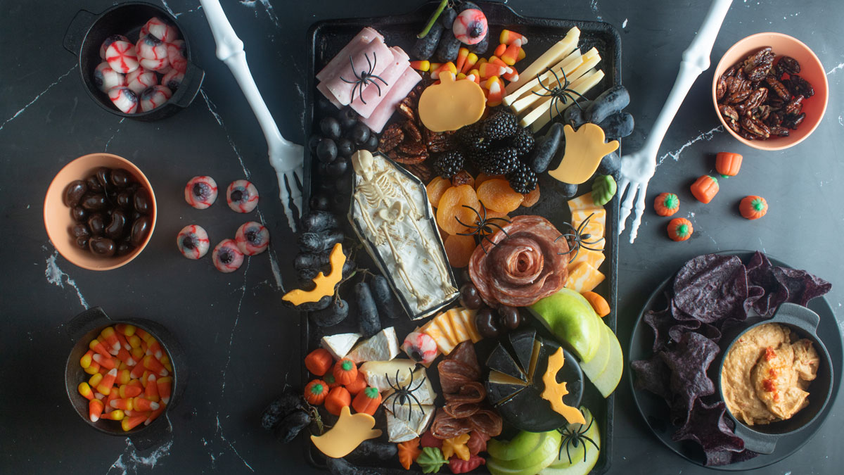 Various fruits, meats, and cheeses on a black board.