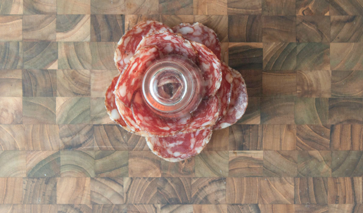 Shot glass turned upside down on a cutting board with the meat.