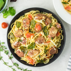 Large bowl of pasta with tomatoes, chorizo and basil.