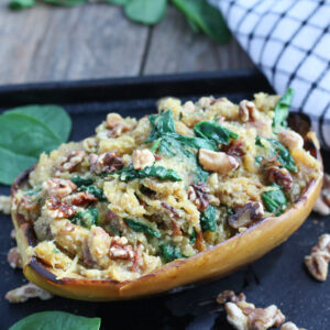 Spaghetti squash stuffed with bacon and spinach and garnished with walnut halves.