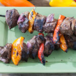 Kebabs with colorful bell peppers on a green tray.