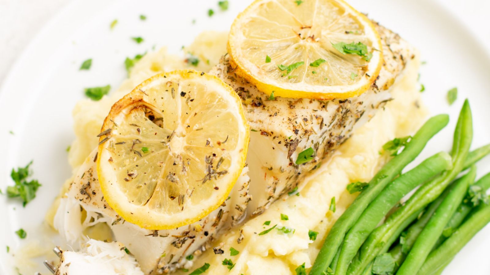 Air fryer halibut with sliced lemons and asparagus.