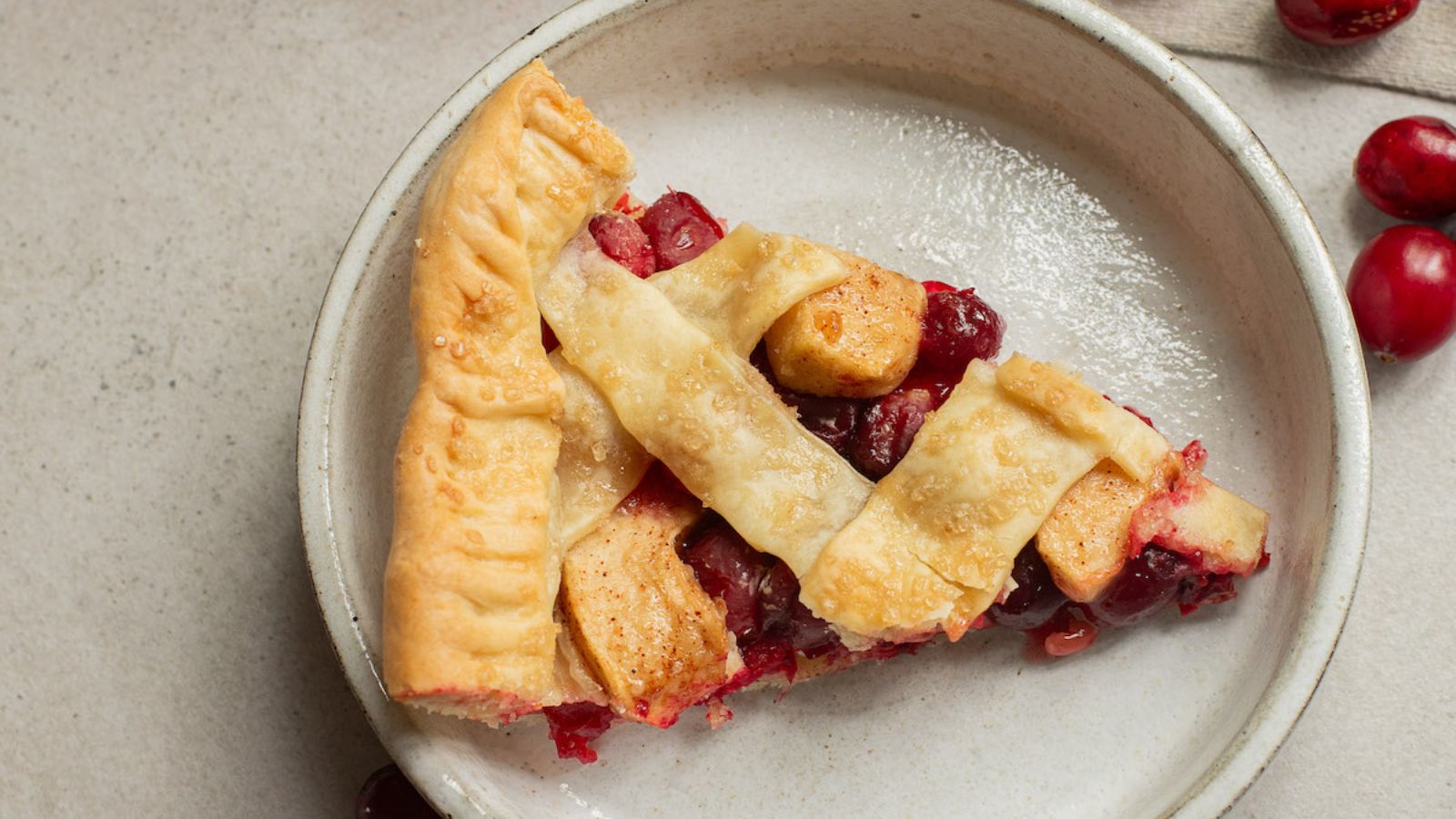 A slice of apple cranberry pie on a plate.