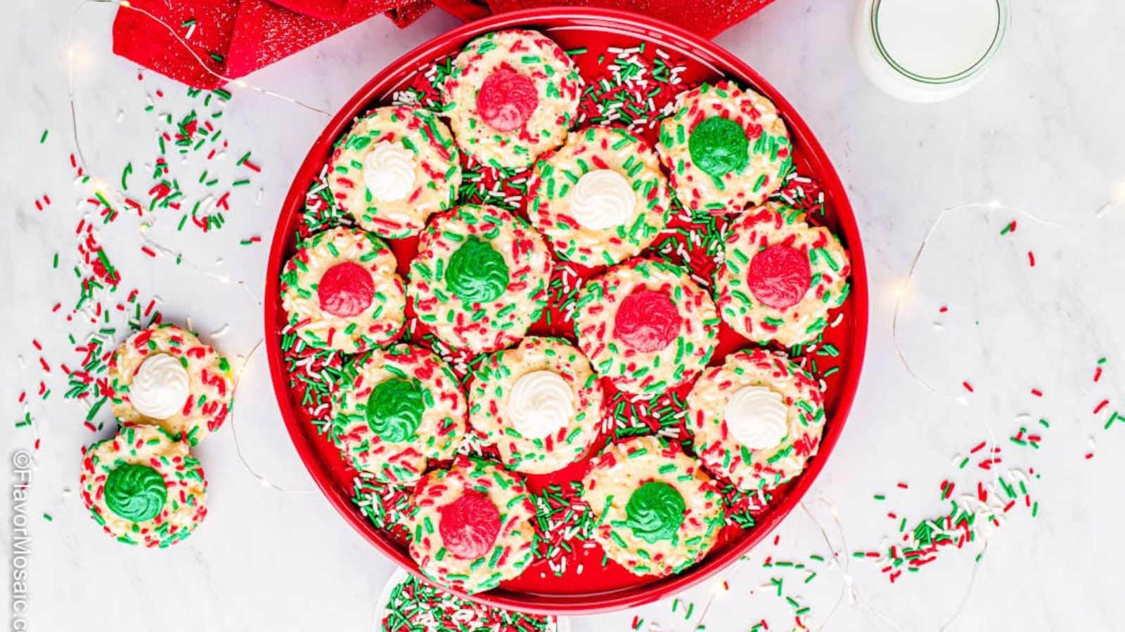 Christmas thumbprint cookies on a red plate.