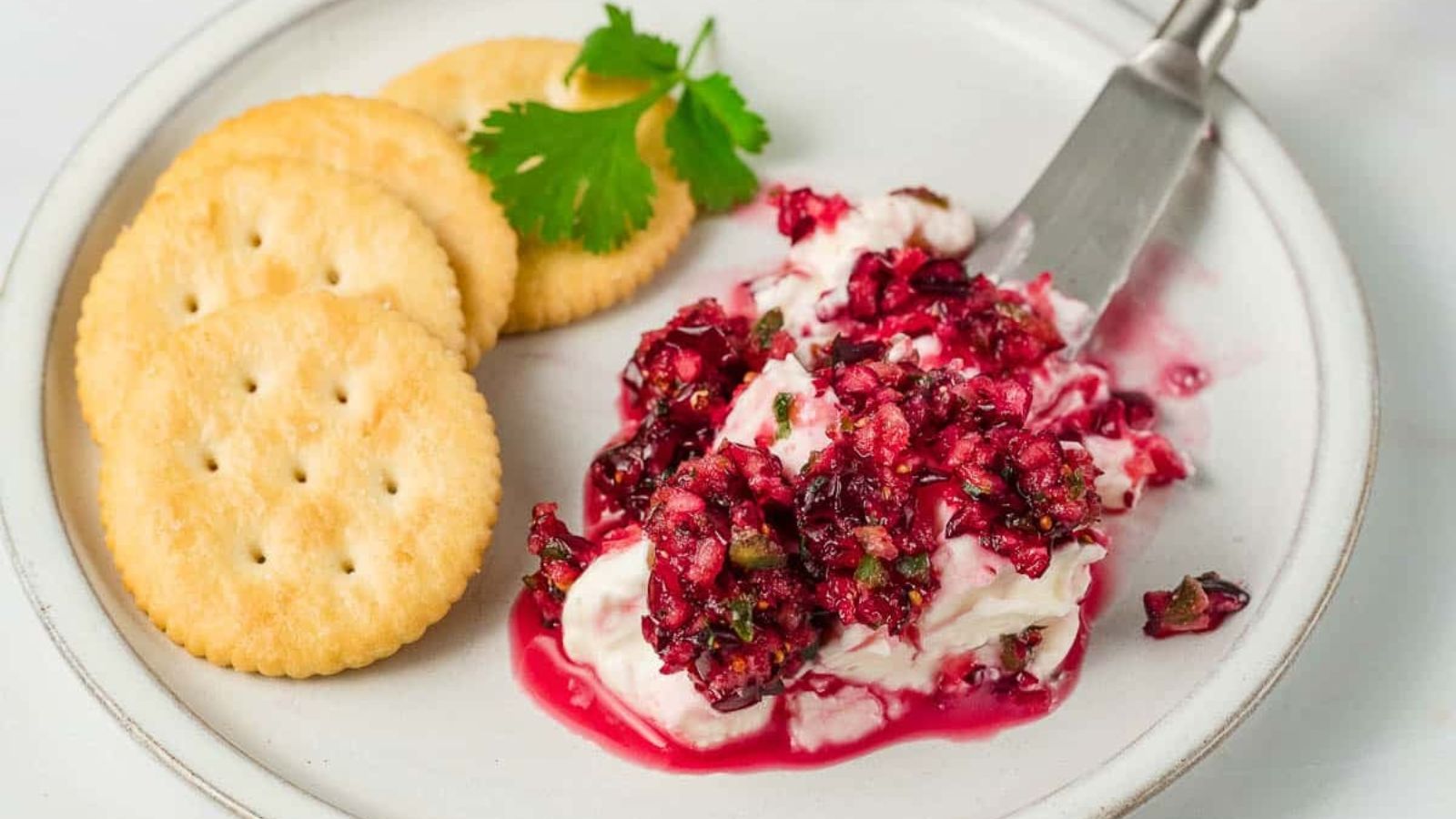 Cream cheese dip with cranberry and crackers on the side.