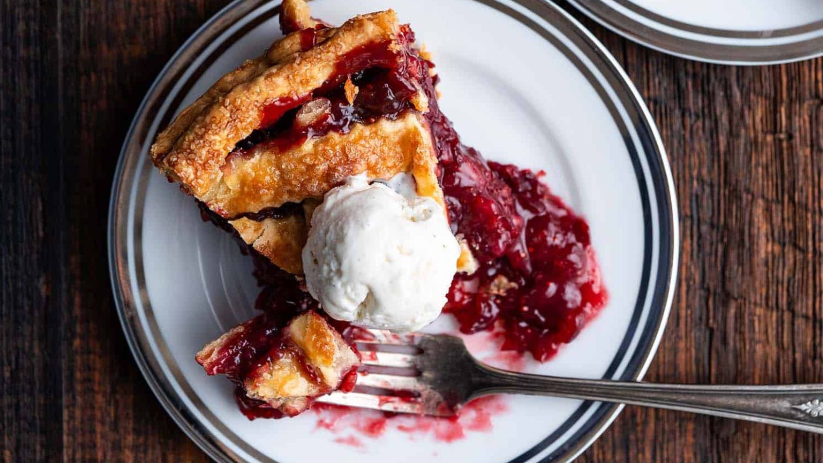 A slice of cranberry pie with a scoop of ice cream.