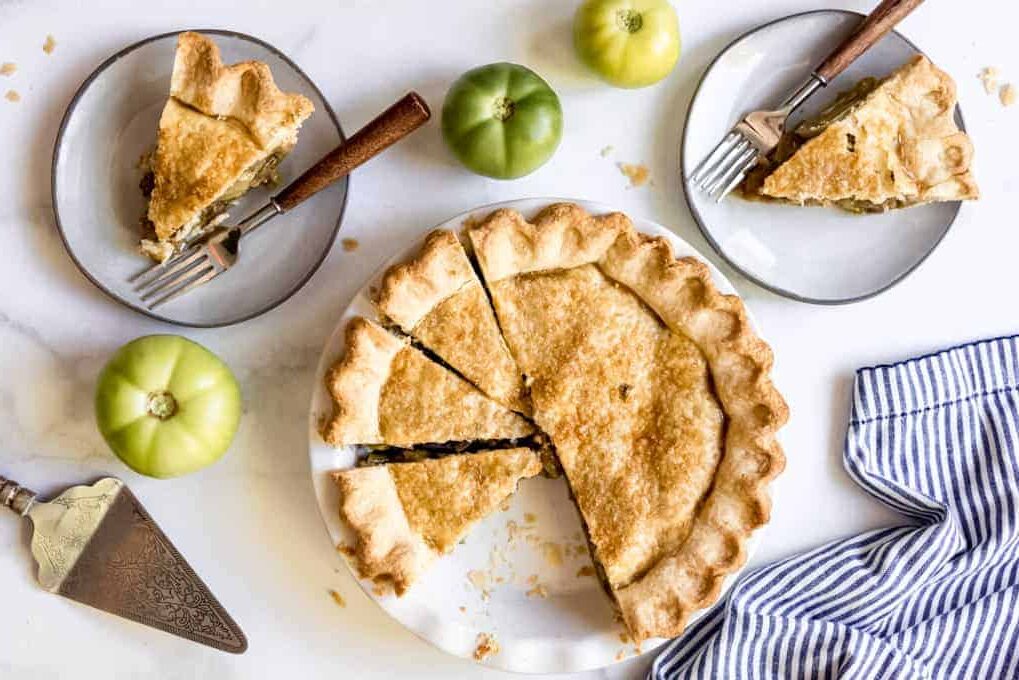 Small plates with pieces of pie next to a pie dish with pieces cut.