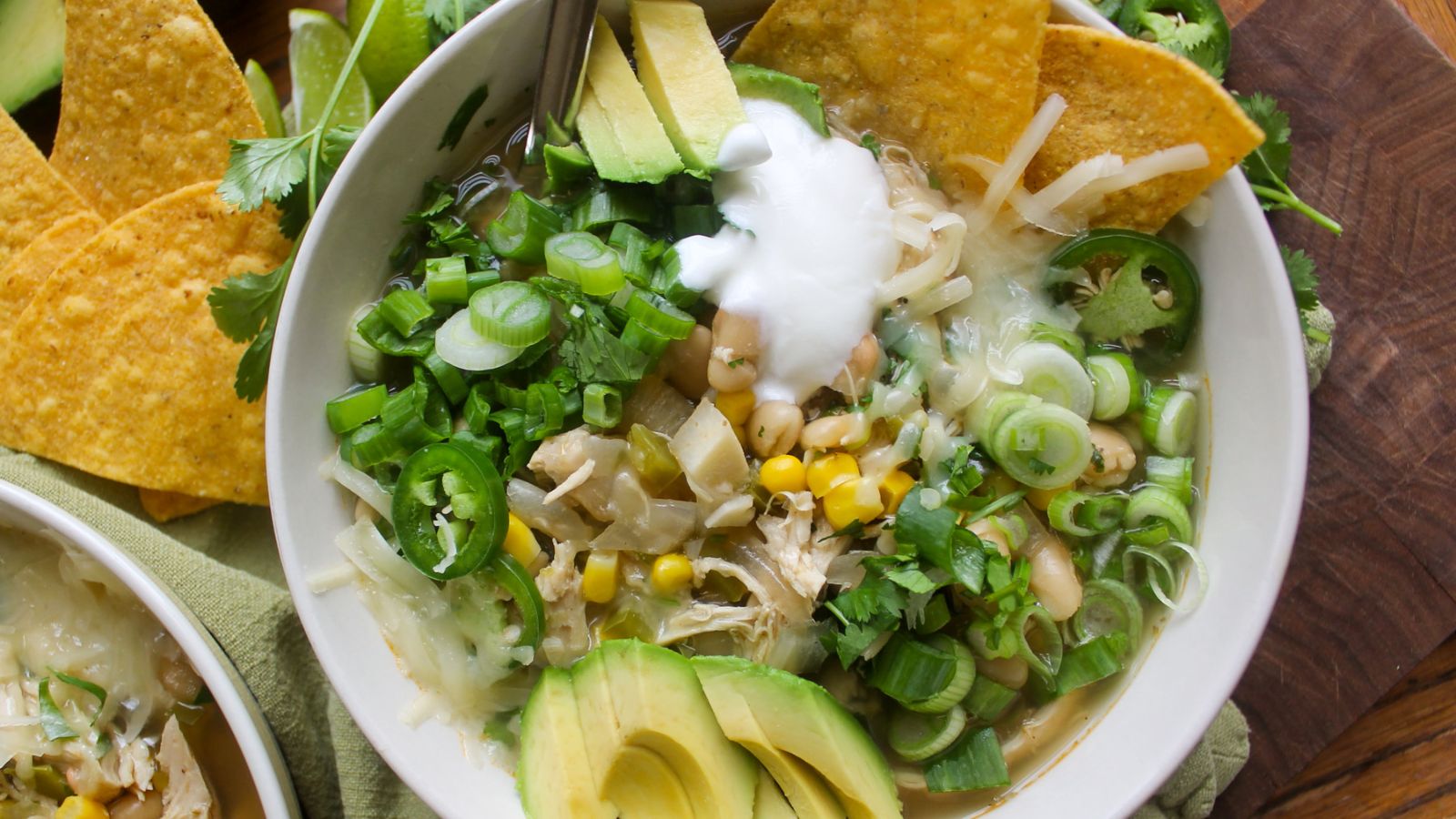 A bowl of white chicken chili with sliced avocados.