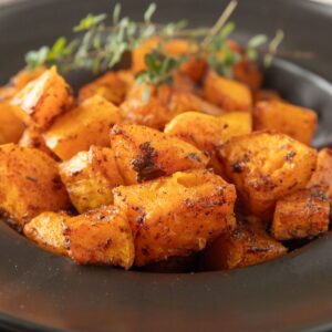 Close up of roasted butternut squash in a black bowl.