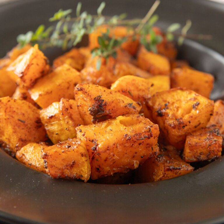 Close up of roasted butternut squash in a black bowl.