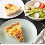 Pieces of quiche on small plates with a salad in a bowl.