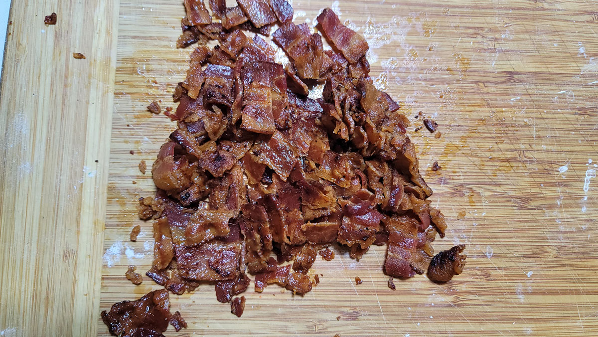 Chopped crispy bacon on a cutting board.
