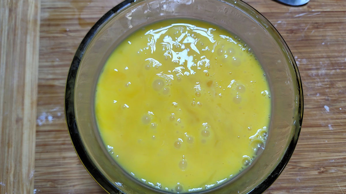 Whisked eggs in a small bowl.