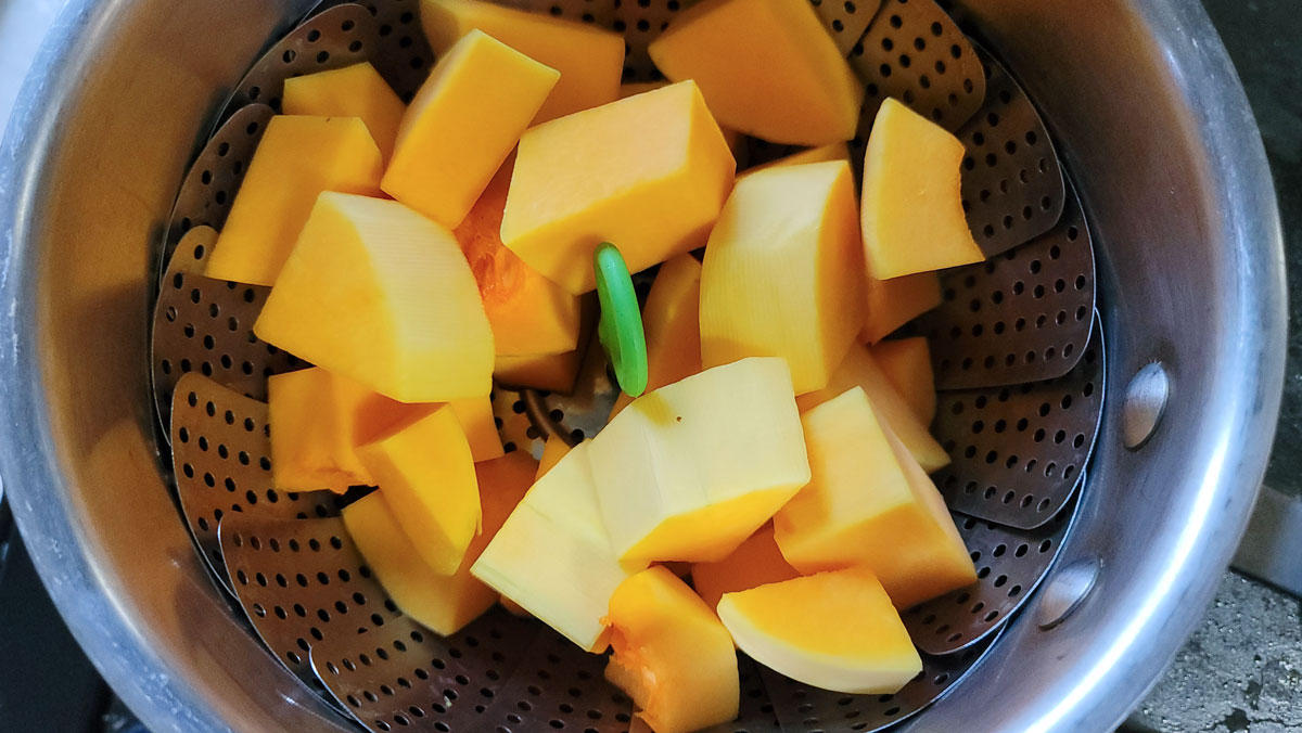 Cubed squash in a steamer pot.
