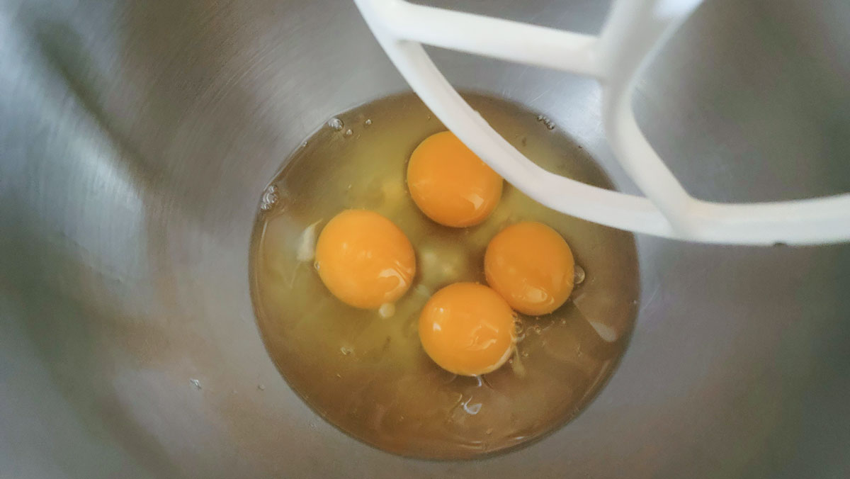 Eggs and oil in the bowl of a stand mixer.