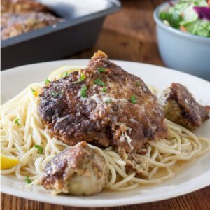 Parsley topped chicken French on a bed of pasta.