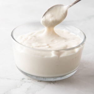 Cream cheese glaze dripping off of a spoon.