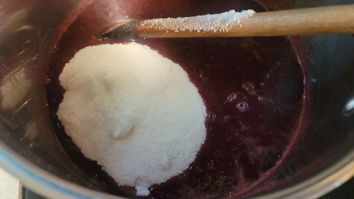 Sugar added to the grape mixture in the pot.