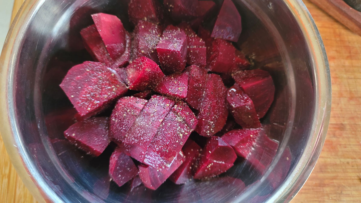 Beet pieces in a bowl with salt, pepper, oil and honey.