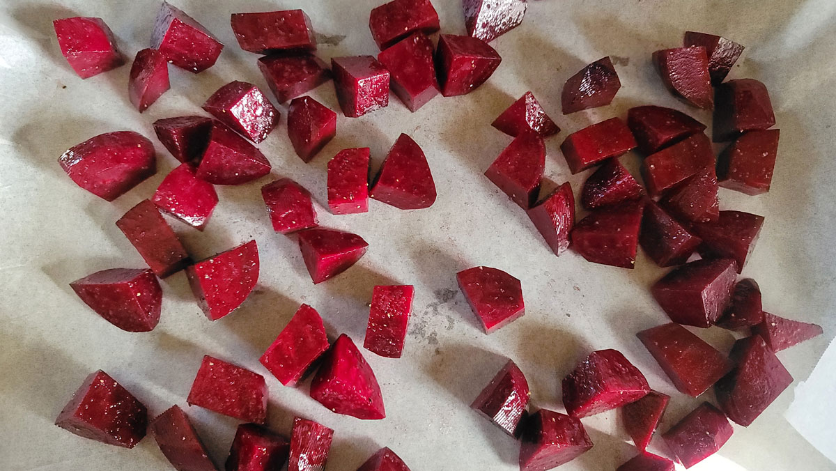 Beets on parchment- lined baking sheet.