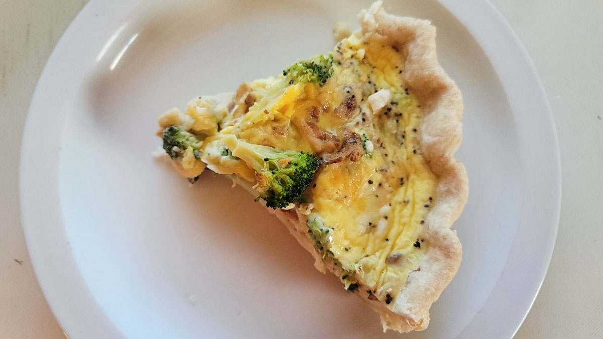 Piece of quiche on a microwave-safe plate.