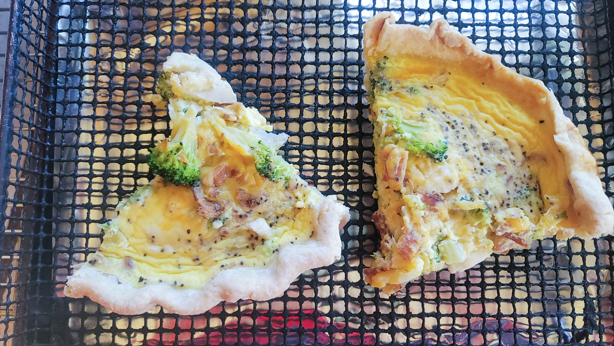 Two pieces of quiche on an air fryer basket.