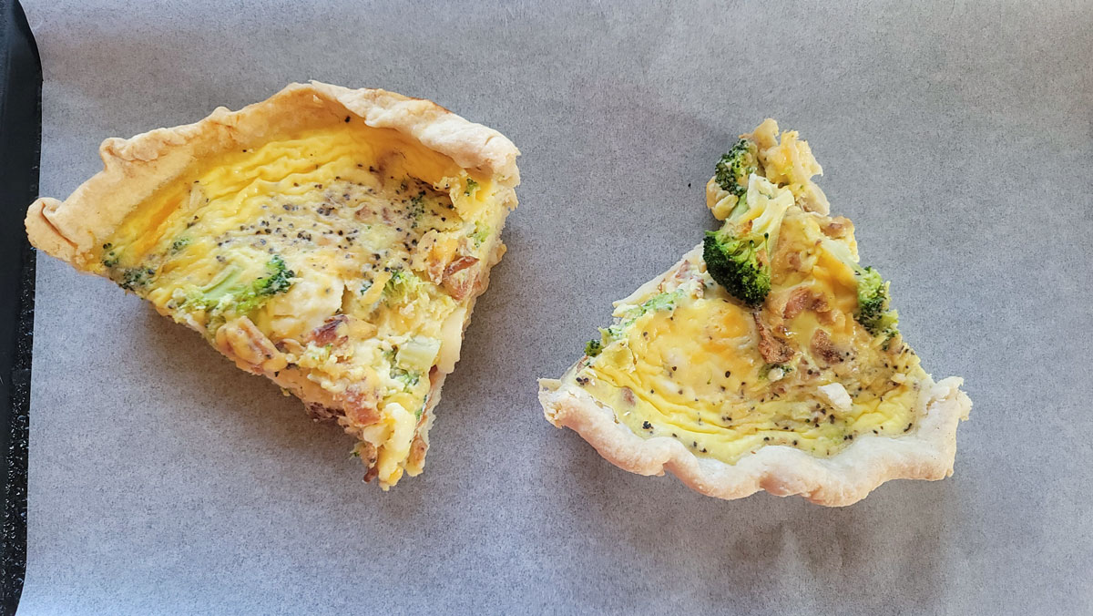 Two pieces of quiche on a parchment covered baking sheet.
