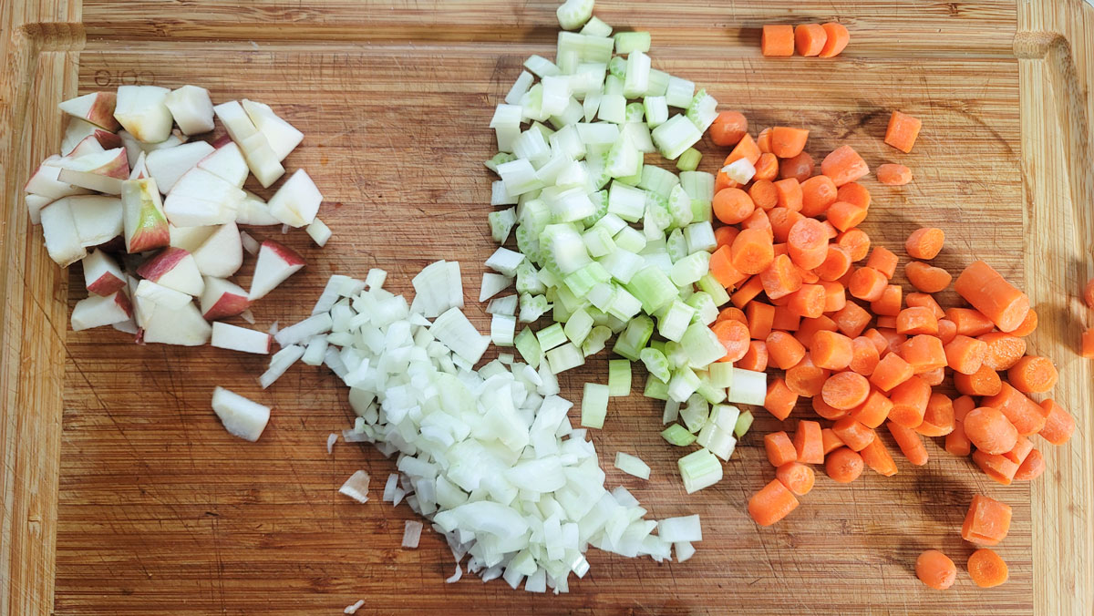 Mirepoix chopped on a cutting board with chopped apples.