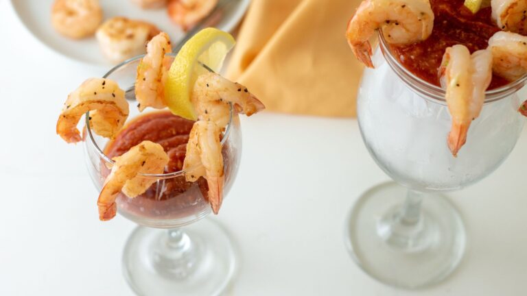 Shrimp cocktail in tall glass filled with ice.