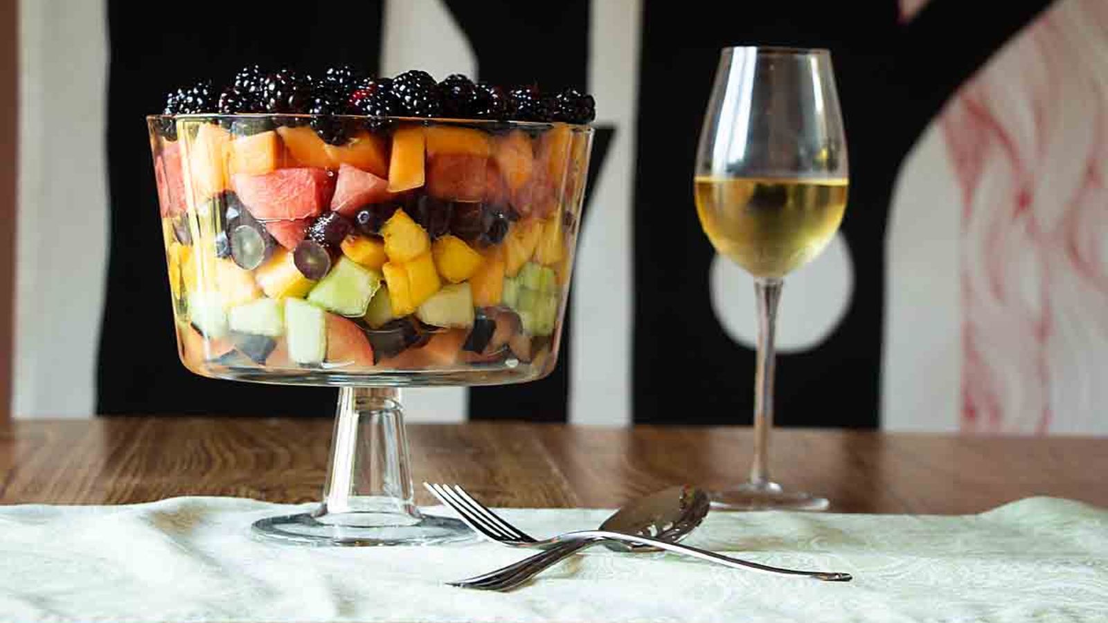 Layered fruit salad in a large footed serving bowl.