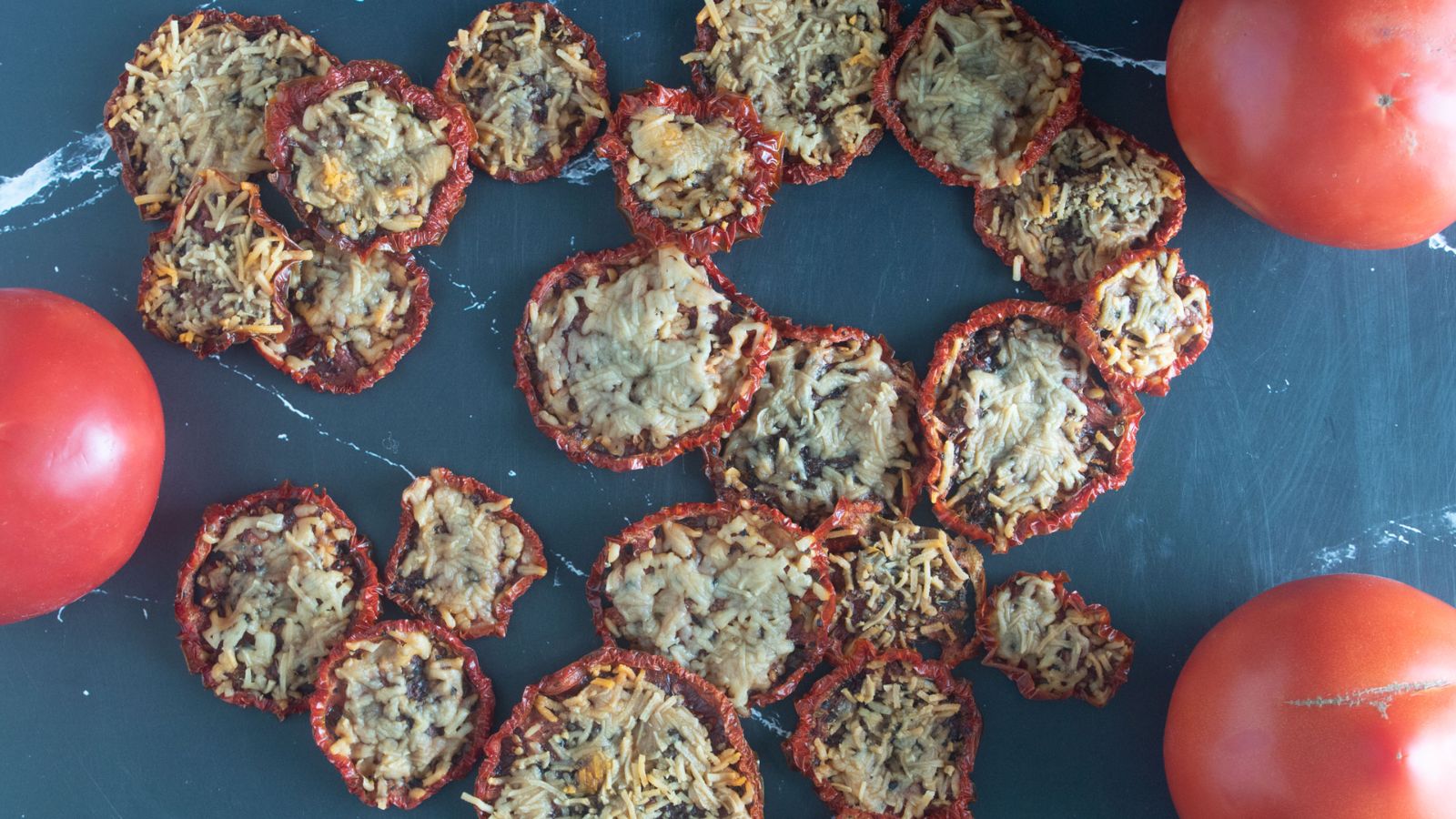Parmesan tomato chips on a black board.