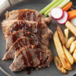 Sliced brisket drizzled with BBQ sauce.