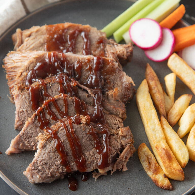 Sliced brisket drizzled with BBQ sauce.
