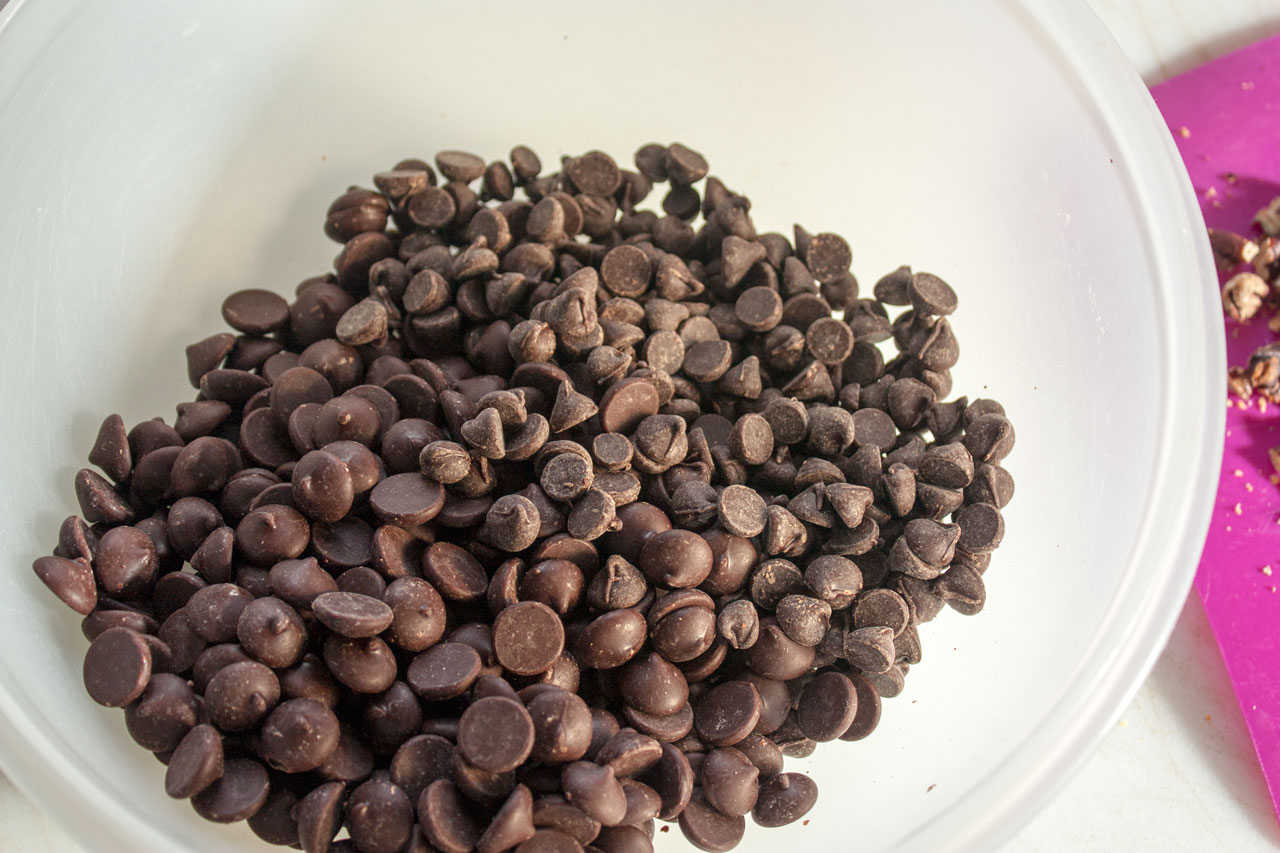 Chocolate chips added to a large plastic bowl.