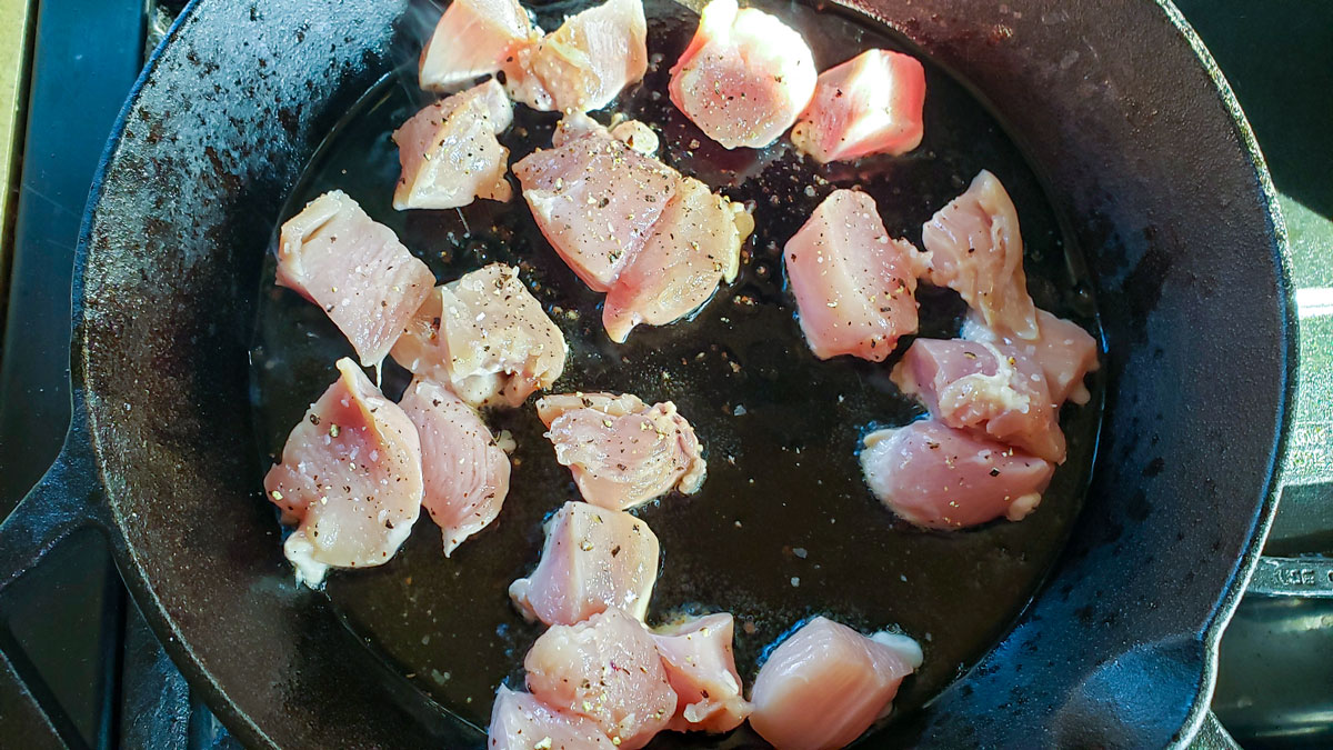 Browning chicken in olive oil in a cast iron skillet.