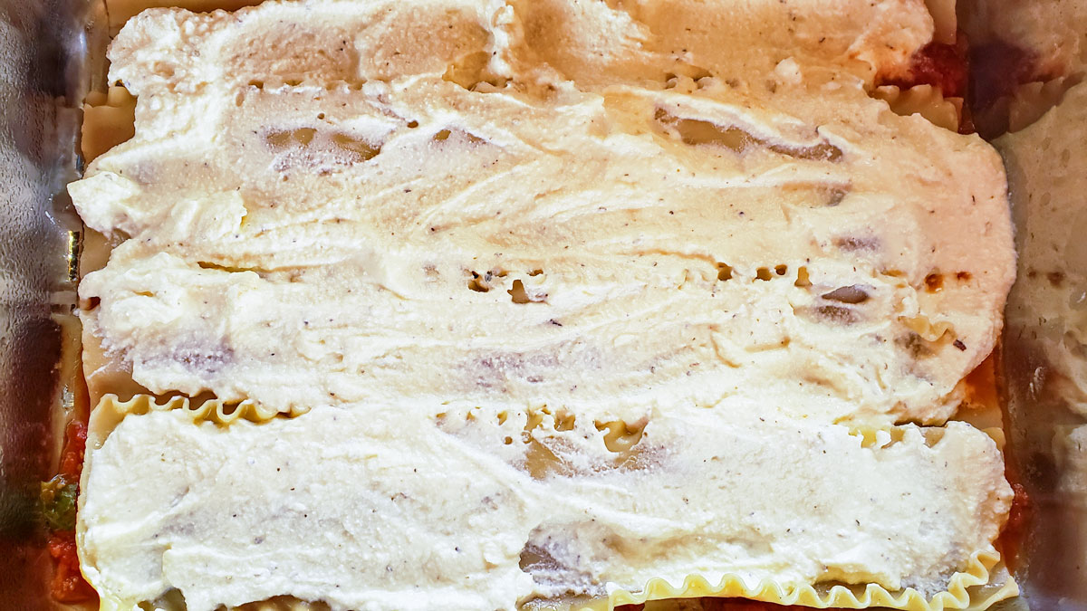 Cheese layer spread on top of the lasagna noodles in the lasagna pan.